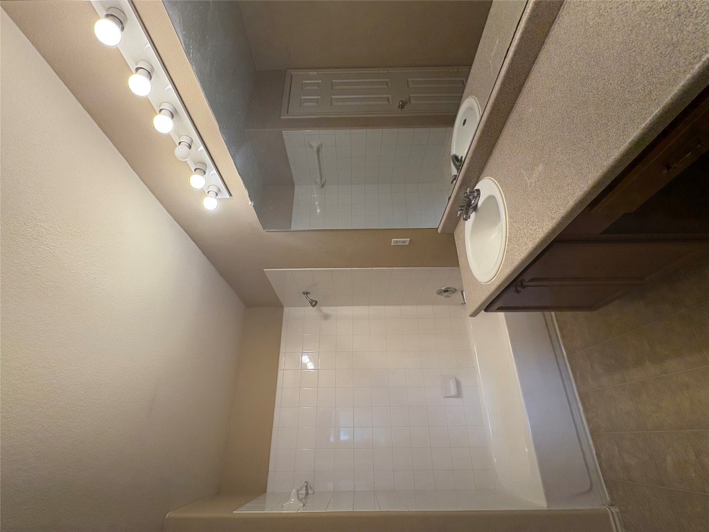 18316 Great Falls Drive Manor, TX 78653 - Photo 16 of 25 a bathroom with a sink a large mirror and a bathtub