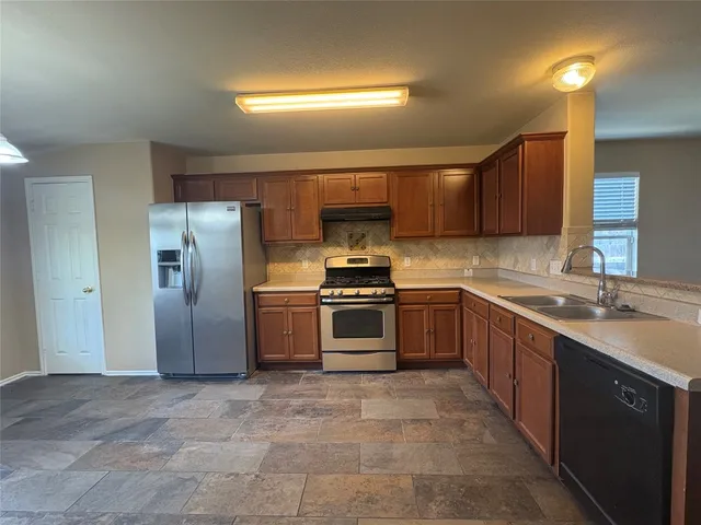 a kitchen with stainless steel appliances granite countertop a stove a sink and a refrigerator