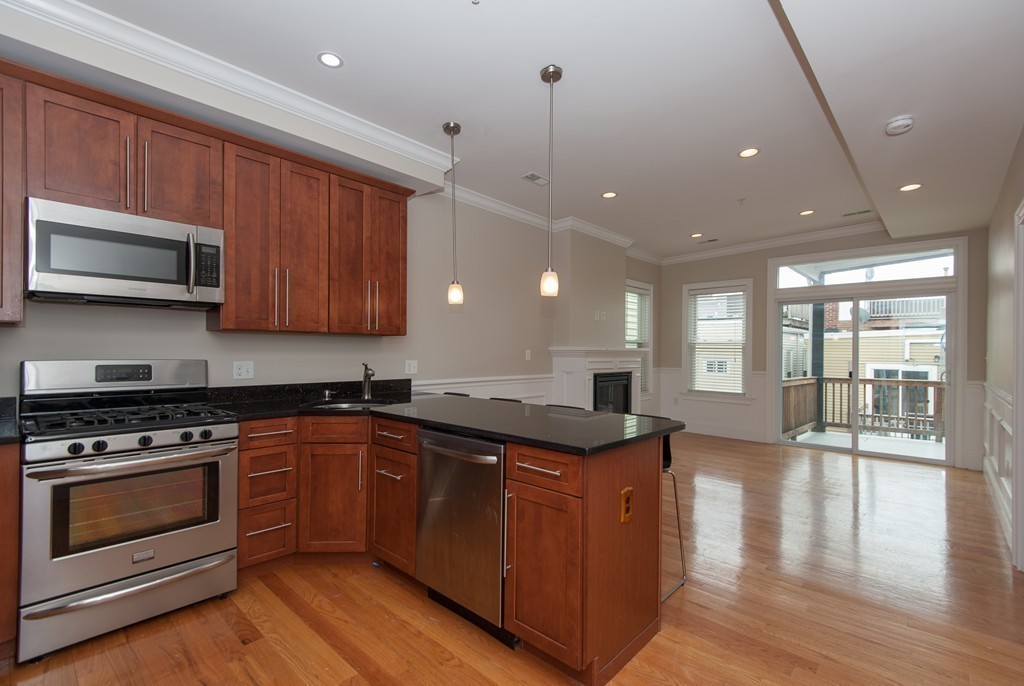 a kitchen with stainless steel appliances granite countertop wooden cabinets granite counter tops and a hard wood floors