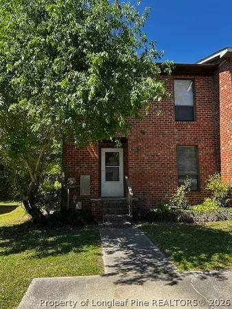 a backyard of a house with plants and large tree