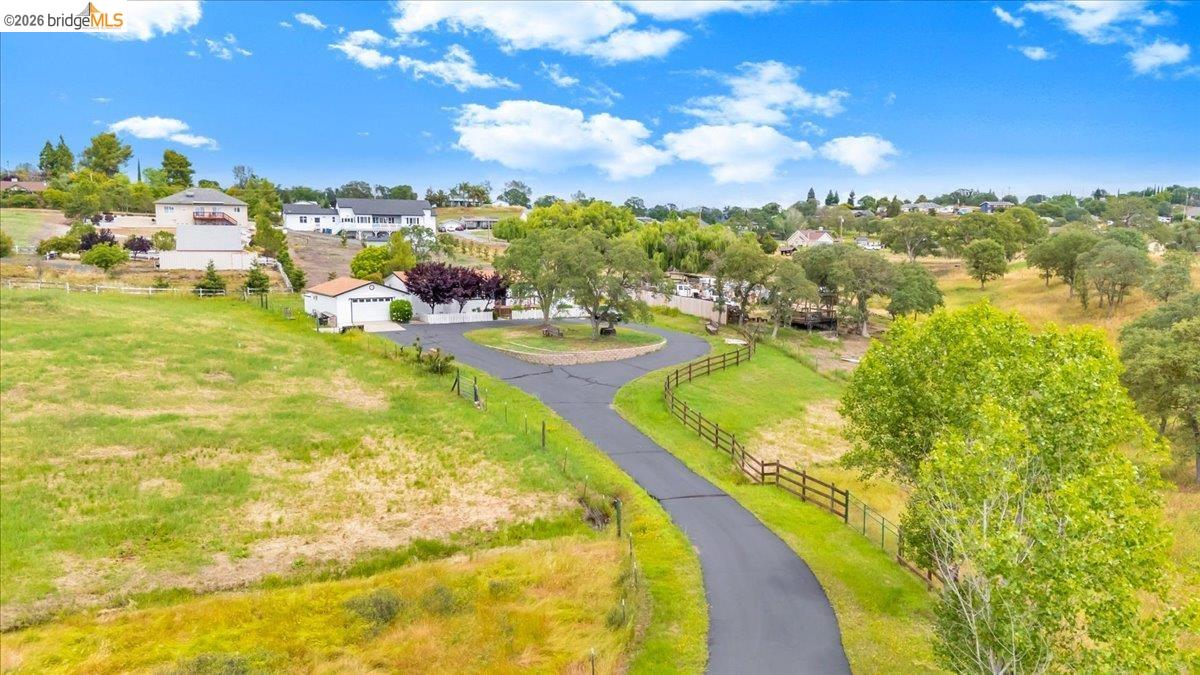 4419 Little John Road Copperopolis, CA 95228 - Photo 36 of 43 Paved private driveway with a circular turnaround, surrounded by mature trees, fenced property boundaries, and verdant open spaces