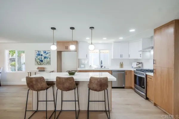 a kitchen with stainless steel appliances granite countertop a stove a sink a refrigerator a dining table and chairs