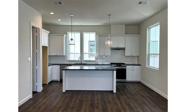 a kitchen with stainless steel appliances granite countertop a stove a sink and a refrigerator