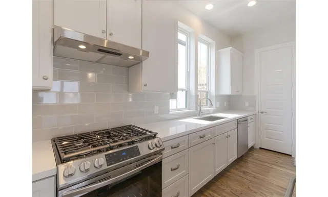 a kitchen with stainless steel appliances a stove a sink and white cabinets