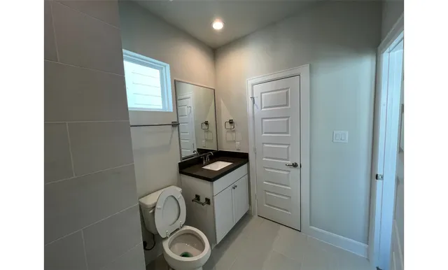 a bathroom with a granite countertop sink and a toilet
