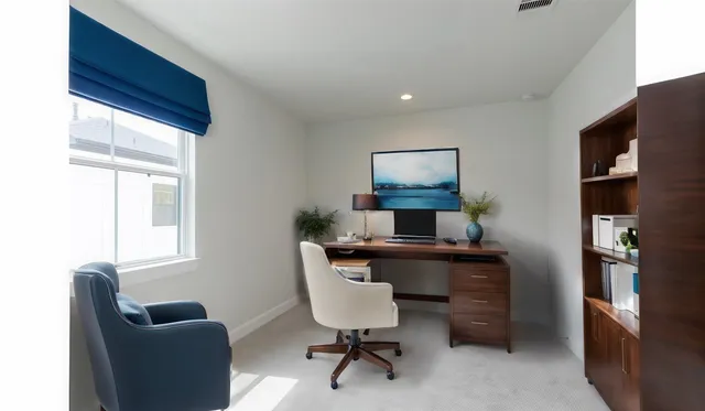 a view of a workspace with furniture and a window