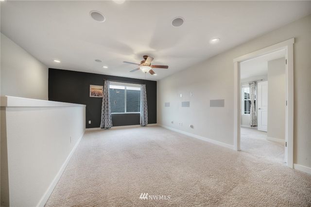 an empty room with windows and ceiling fan