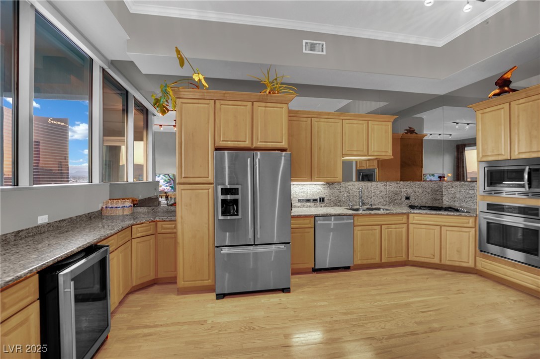 360 East Desert Inn Road, Unit 1803 Las Vegas, NV 89109 - Photo 39 of 67 Kitchen featuring appliances with stainless steel finishes, beverage cooler, light brown cabinets, light wood-type flooring, and crown molding