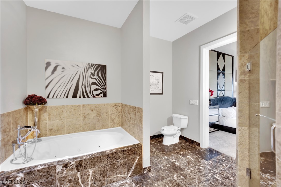 360 East Desert Inn Road, Unit 1803 Las Vegas, NV 89109 - Photo 49 of 67 Bathroom with toilet, a whirlpool tub, ensuite bath, baseboards, and lofted ceiling