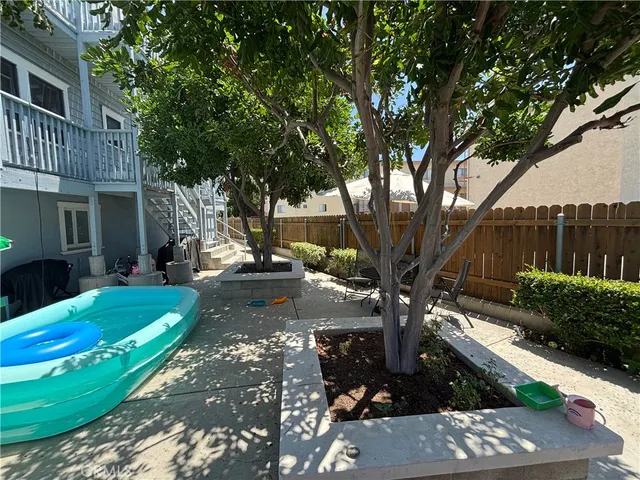 a view of a backyard with table and chairs plants and wooden fence