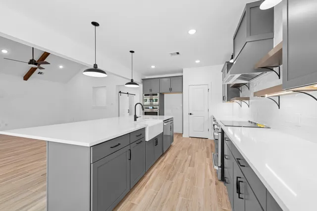 a large white kitchen with wooden floor and a sink