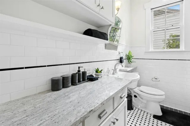 a bathroom with a granite countertop sink a toilet and mirror