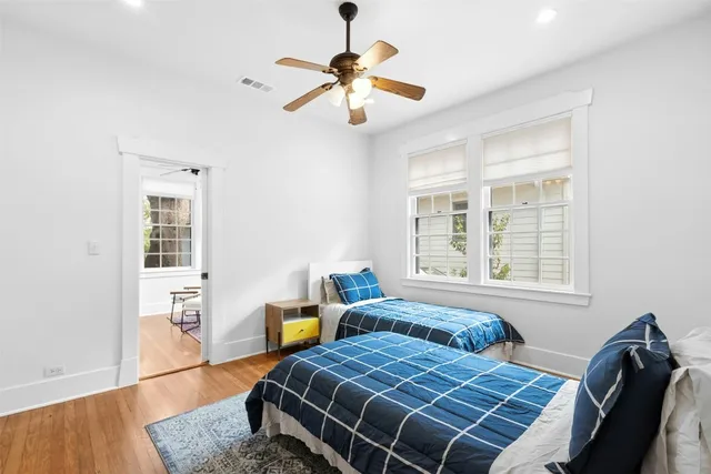 a bedroom with two beds and wooden floor