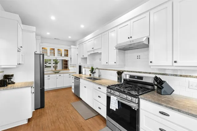 a kitchen with kitchen island granite countertop a sink a stove and refrigerator