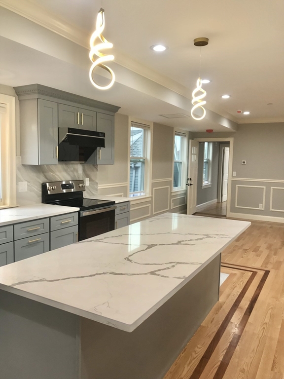 a kitchen with kitchen island granite countertop a stove and a sink