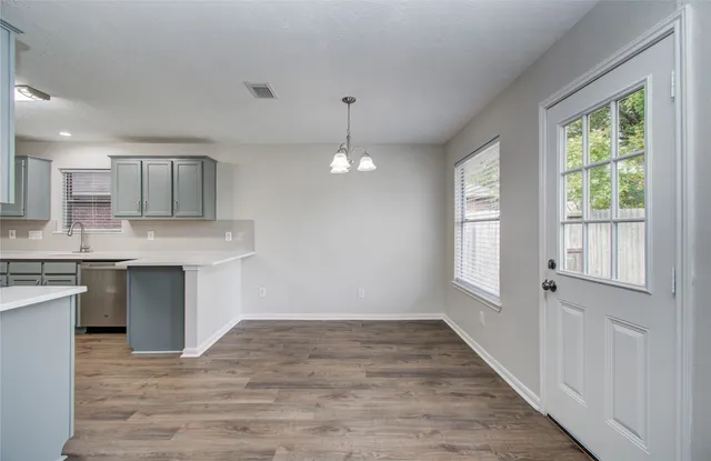 a kitchen with granite countertop a stove a sink and white cabinets with wooden floor