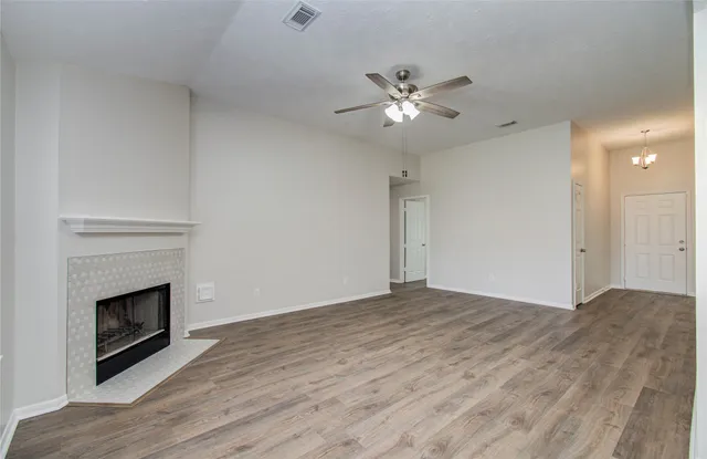 a view of an empty room with wooden floor and a fireplace