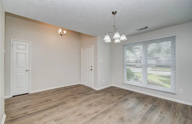 a view of a livingroom with a chandelier wooden floor and chandelier