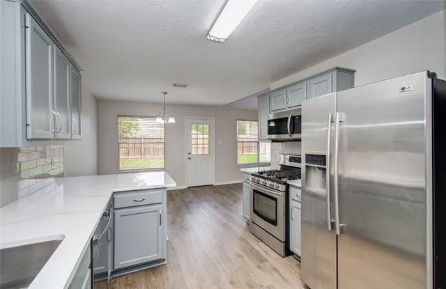 a kitchen with granite countertop a refrigerator a sink a stove and cabinets