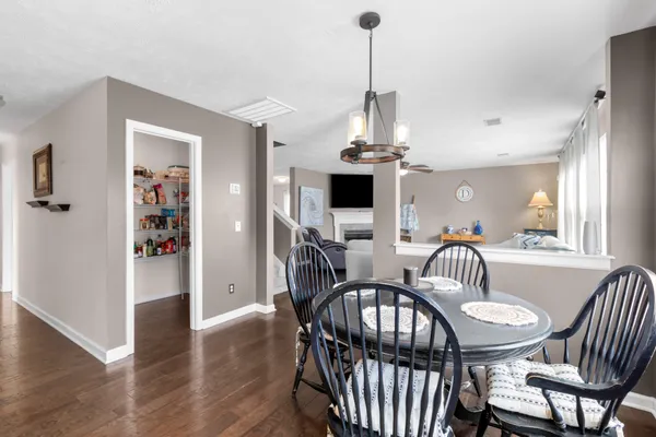 a kitchen with stainless steel appliances a refrigerator a stove a dining table and chairs with wooden floor