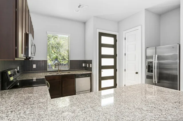 a kitchen with granite countertop a refrigerator and a sink