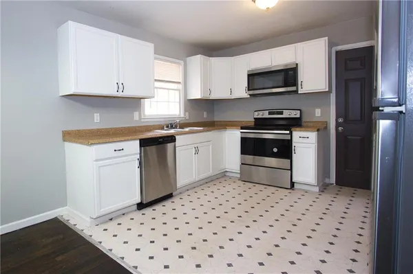 a kitchen with a sink a stove top oven and white stainless steel appliances