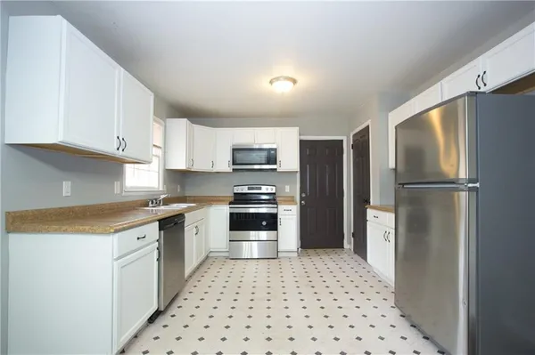 a kitchen with granite countertop a refrigerator and a stove top oven