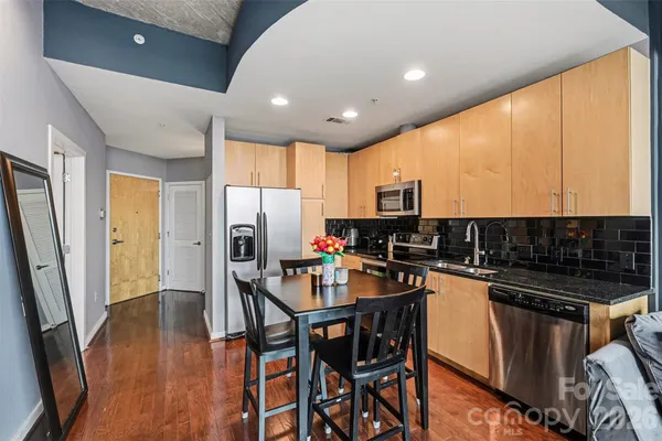 a kitchen with stainless steel appliances a refrigerator a stove a sink cabinets and a dining table