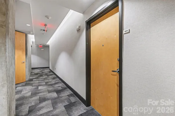 a view of a hallway with wooden floor and a bathroom