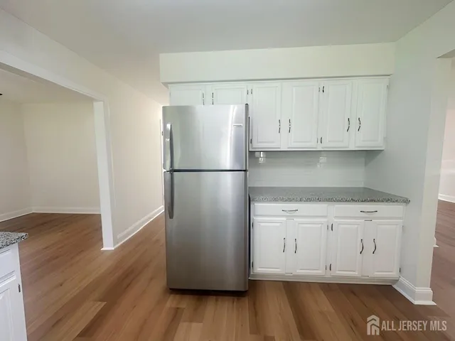 a kitchen with wooden floors white cabinets and a refrigerator