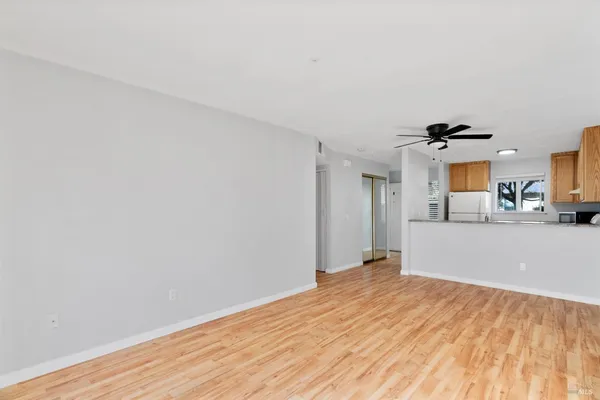 a view of a big room with wooden floor and kitchen view