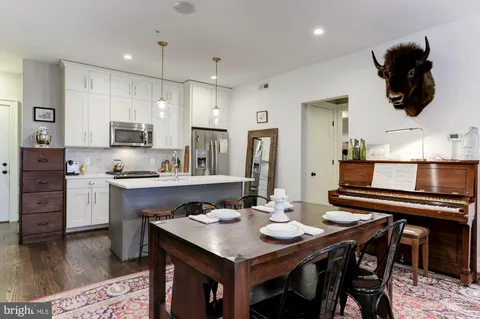 a kitchen with stainless steel appliances granite countertop a dining table chairs stove refrigerator and cabinets