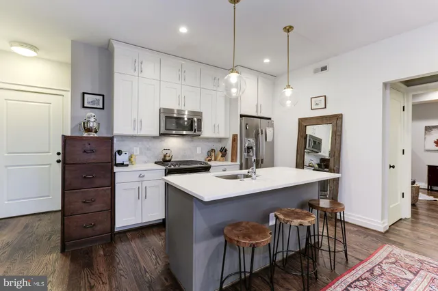 a kitchen with stainless steel appliances granite countertop a stove top oven a sink a dining table and chairs with wooden floor