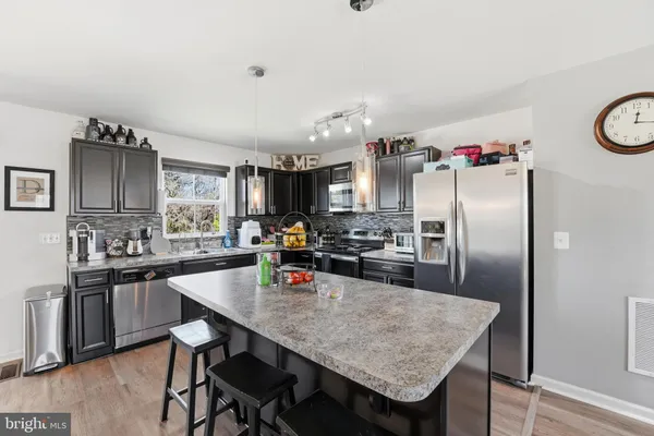 a kitchen with granite countertop a table chairs stove and refrigerator