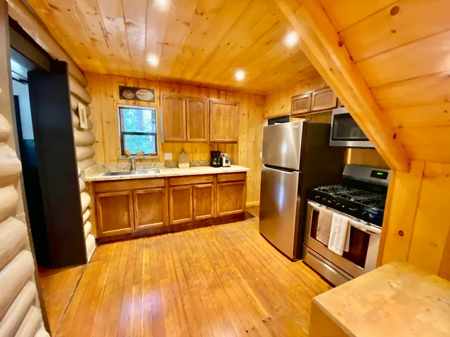 a kitchen with stainless steel appliances a refrigerator a sink a stove and wooden cabinets