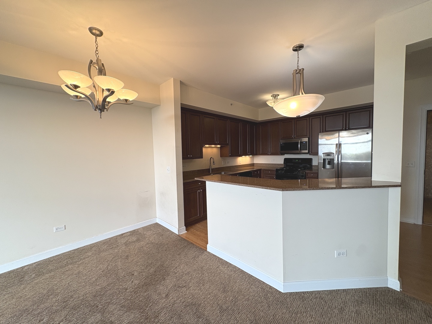 8300 Callie Avenue, Unit 610 Morton Grove, IL 60053 - Photo 12 of 32 a kitchen with kitchen island granite countertop a table and chandelier