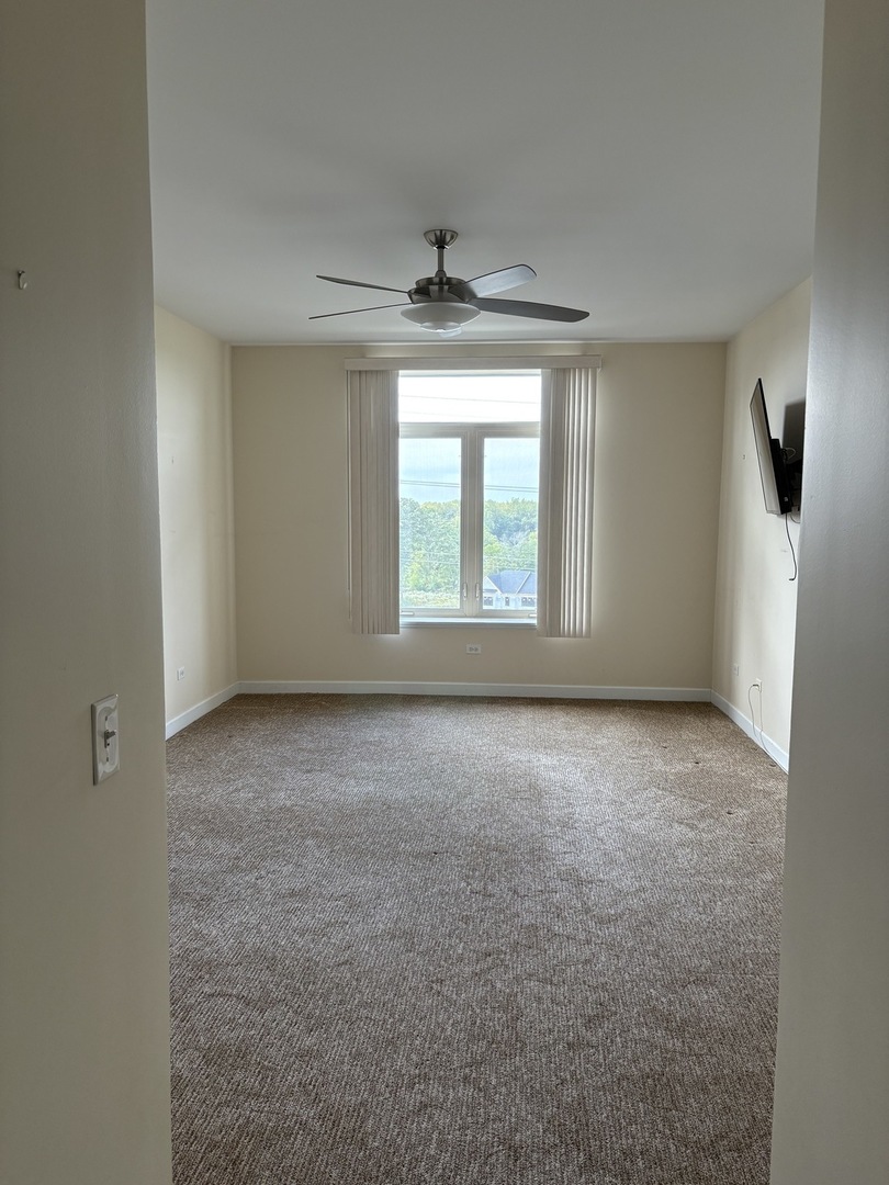 8300 Callie Avenue, Unit 610 Morton Grove, IL 60053 - Photo 14 of 32 an empty room with a chandelier fan and windows