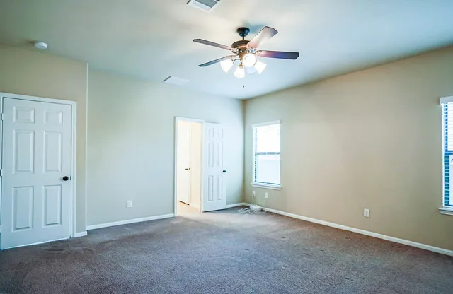 an empty room with a window and a ceiling fan