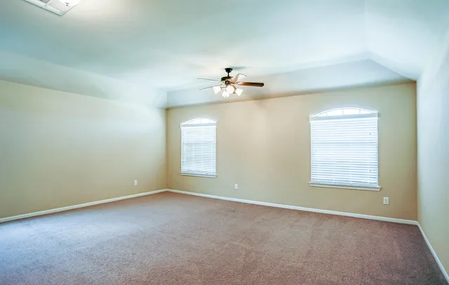 a view of an empty room and chandelier fan
