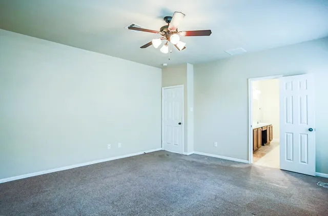 en empty room with windows and ceiling fan