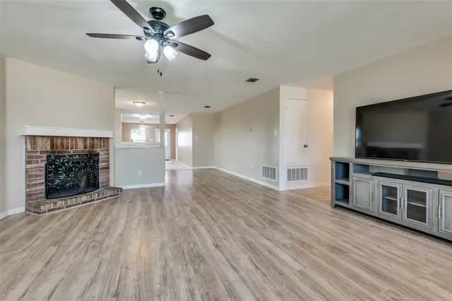 a view of a livingroom with a flat screen tv a ceiling fan and wooden floor