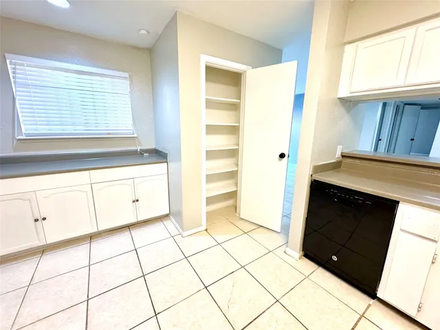 a kitchen with granite countertop white cabinets and window