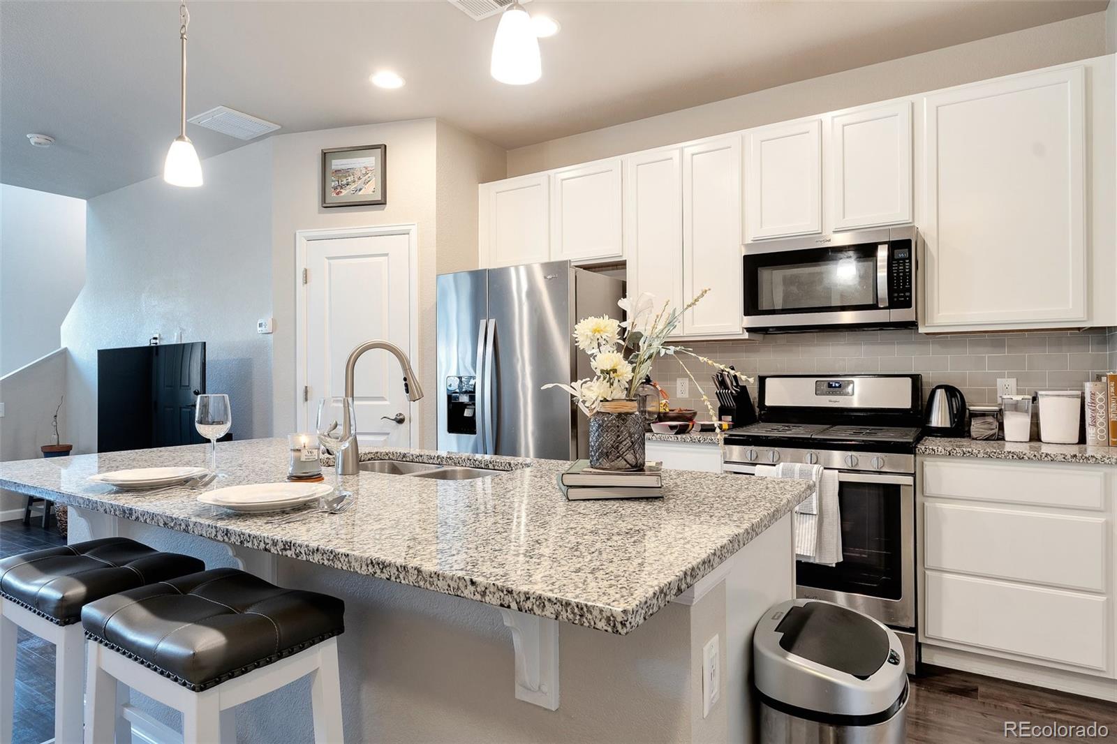 a kitchen with granite countertop kitchen island stainless steel appliances a stove microwave and sink