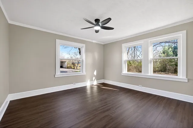 a view of an empty room with wooden floor and a window