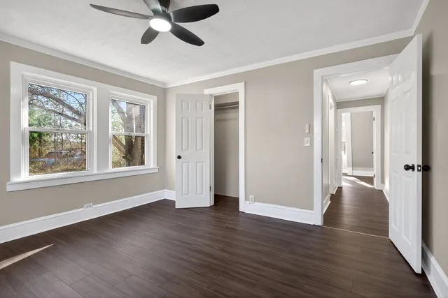 a view of an empty room with wooden floor and a window