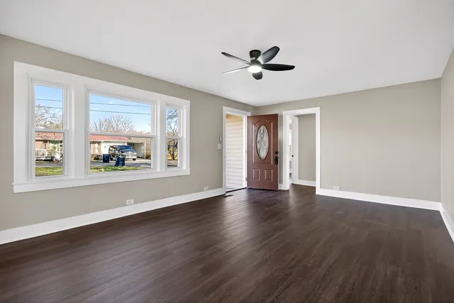 a view of an empty room with window and wooden floor
