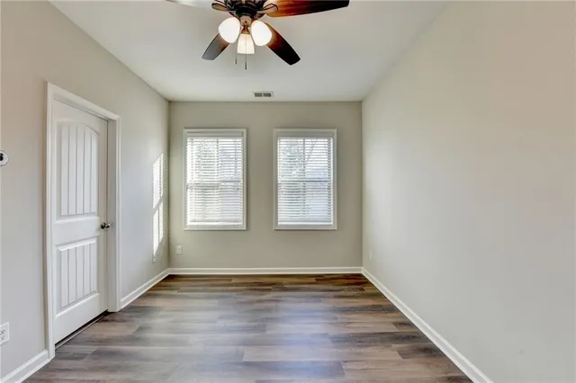 a view of an empty room with wooden floor and window