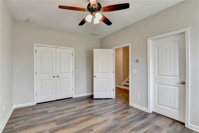 a view of empty room with wooden floor and ceiling fan