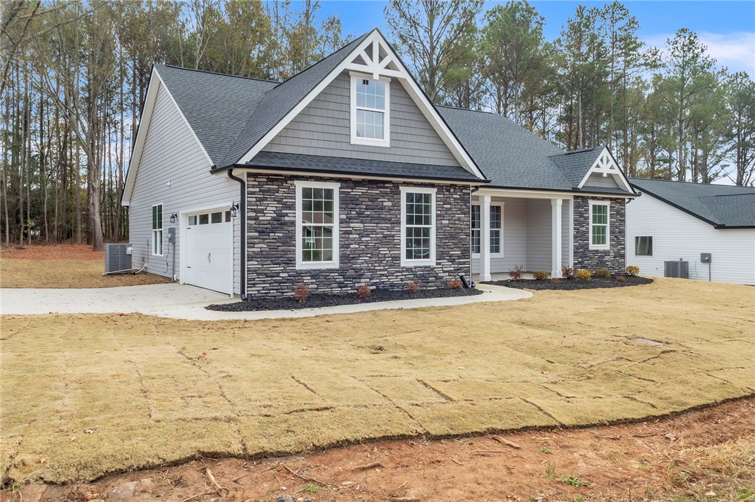 121 Ashley Drive Pelzer, SC 29669 - Photo 2 of 25 View of front of home with stone siding, covered porch, a shingled roof, and driveway