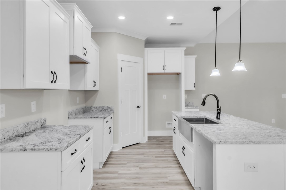 121 Ashley Drive Pelzer, SC 29669 - Photo 8 of 25 Kitchen featuring decorative light fixtures, white cabinets, an island with sink, crown molding, and light stone counters